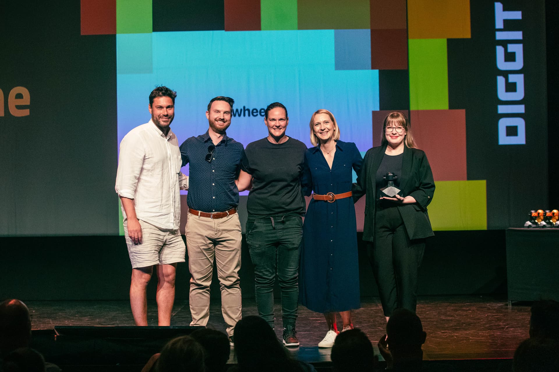 Five people standing side by side on stage at the DIGGIT event, posing for a group photo in front of a large screen displaying the CNJ Digital and Sweephub brand names. The background features a colorful digital design with the DIGGIT logo on the right. The group is smiling and appears to have received an award.